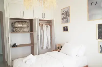 a bedroom with a white bed and white cabinets at Happiness Apartment in Ouarzazate