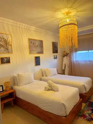 two beds in a bedroom with a chandelier at Happiness Apartment in Ouarzazate