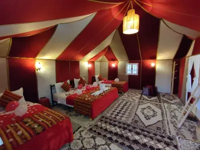 a room with two beds and a red and white ceiling at Merzouga Desert Night Luxury Camp Tours & Cozy Rooms in Rissani