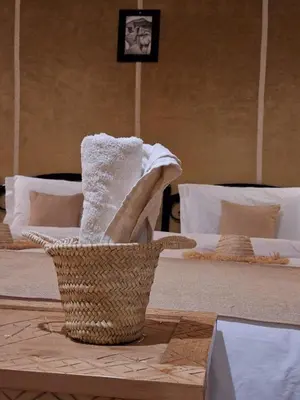 a basket of towels on a table next to a bed at Merzouga Desert Night Luxury Camp Tours & Cozy Rooms in Rissani