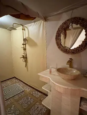 a bathroom with a sink and a mirror at Merzouga Desert Night Luxury Camp Tours & Cozy Rooms in Rissani