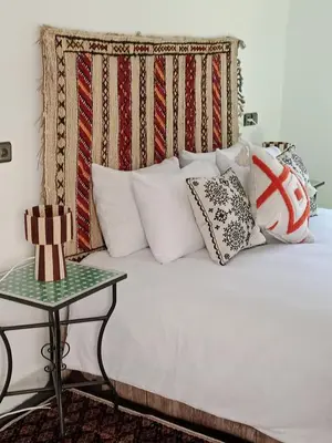 a bed with many pillows on it with a table at Riad la Fíbula de Nora in Fès