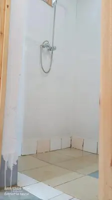a shower in a white room with a tile floor at StarlitDesertCamp in El Gouera