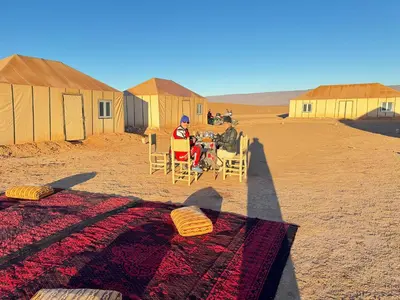 a man sitting in chairs in the middle of a desert at StarlitDesertCamp in El Gouera