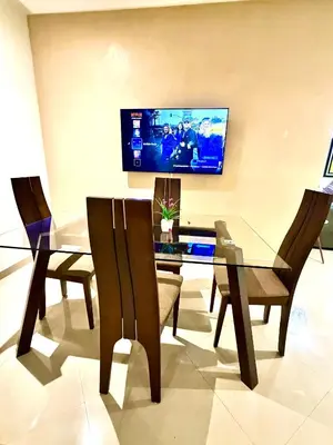 a dining room with a glass table with chairs and a tv at Appartement avec vue sur parc et Wifi 100 Mo in Fès