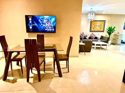 a living room with a table and a tv on the wall at Appartement avec vue sur parc et Wifi 100 Mo in Fès