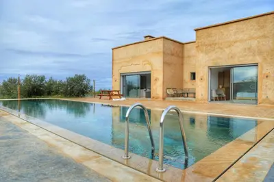 a swimming pool in front of a house at Le Clos des Oliviers Marrakech Villa & Piscine in Marrakech