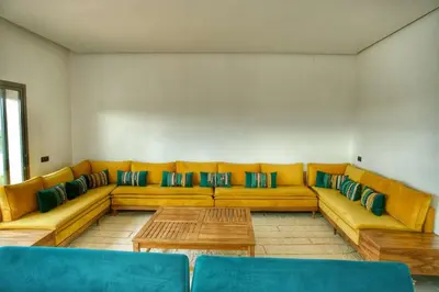 a living room with a yellow couch and a table at Le Clos des Oliviers Marrakech Villa & Piscine in Marrakech