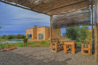 a pavilion with a table and benches in front of a house at Le Clos des Oliviers Marrakech Villa & Piscine in Marrakech