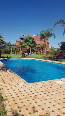 a large blue swimming pool in front of a house at Authentic Riad with swimming pool and private garden