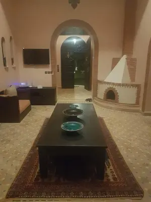 a living room with a table and a fireplace at Authentic Riad with swimming pool and private garden