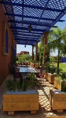 a patio with a table and chairs under a pergola at Authentic Riad with swimming pool and private garden