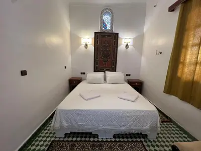 a bedroom with a bed with white sheets and a window at Riad Dar Oum Albanin in Fès