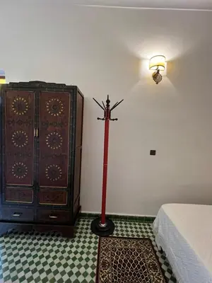 a room with a dresser and a red floor lamp next to a bed at Riad Dar Oum Albanin in Fès