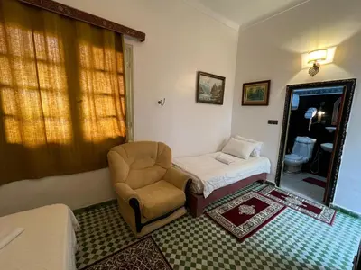a room with a bed and a chair and a mirror at Riad Dar Oum Albanin in Fès