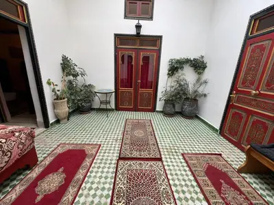 a room with a red door and some rugs at Riad Dar Oum Albanin in Fès