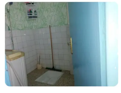 a bathroom with a white tiled wall and a door at fes city in Fès