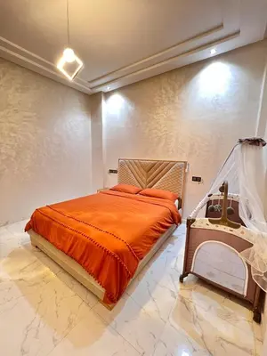 a bedroom with a bed with an orange comforter at White Cactus in Meknès
