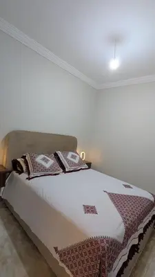 a bed in a white room with a bedspread on it at NAYA apartment in Fès