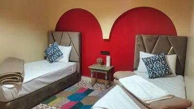 two beds in a room with red walls at Kasbat Taslit in Ouarzazate