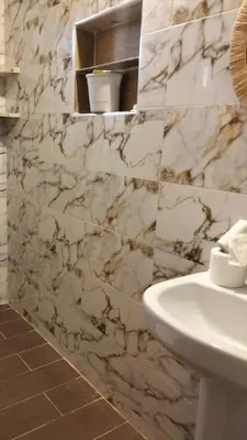 a bathroom with a white sink and a marble wall at Kasbat Taslit in Ouarzazate