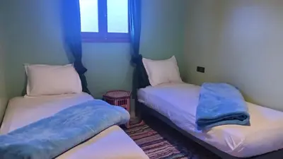 two twin beds in a room with a window at Kasbat Taslit in Ouarzazate