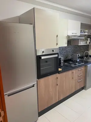 a kitchen with a stainless steel refrigerator and wooden cabinets at Luxury two bedroom apartment Prestigia Fez in Fès