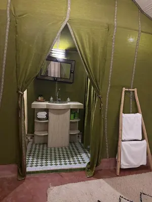 a green bathroom with a sink and a mirror at Dunes Luxury Lodge in Merzouga