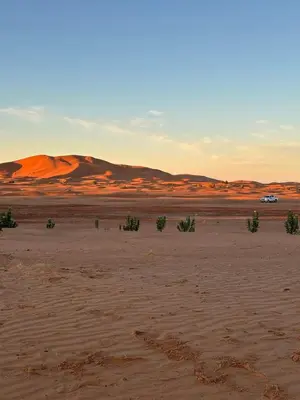 a desert with a car driving in the distance at Dunes Luxury Lodge in Merzouga