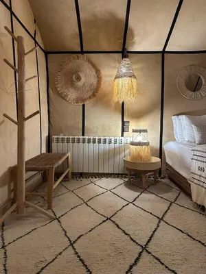 a bedroom with a bed and a table and a bench at Dunes Luxury Lodge in Merzouga