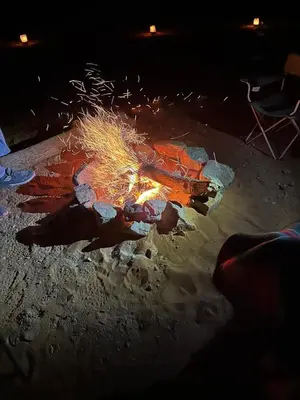 a fire pit in the sand at night at Merzouga Outdoors Private Nomad Expedition in Merzouga