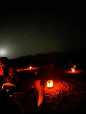 a person sitting on a beach at night with candles at Merzouga Outdoors Private Nomad Expedition in Merzouga