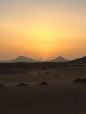 a sunset in the desert with mountains in the background at Merzouga Outdoors Private Nomad Expedition in Merzouga