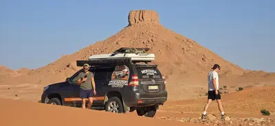 two men standing in front of a truck in the desert at Merzouga Outdoors Private Nomad Expedition in Merzouga