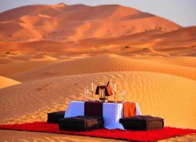 a table in the middle of a desert at Merzouga Luxury Camp in Merzouga