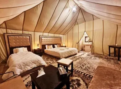 a large room with two beds in a tent at Merzouga Luxury Camp in Merzouga