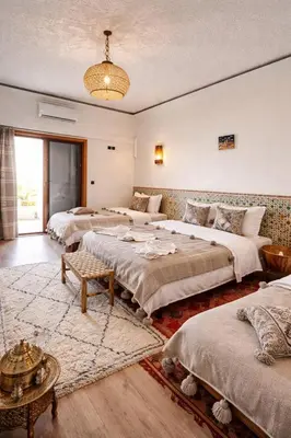 a large bedroom with four beds and a chandelier at Hotel Soleil Blue in Boumalne
