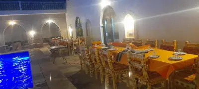 a restaurant with a table and chairs and a swimming pool at Camels house apartment in Hassilabied