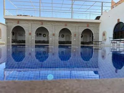 a swimming pool with blue tiles in a building at Camels house apartment in Hassilabied