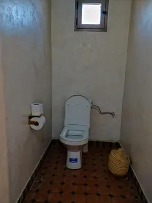 a small bathroom with a toilet and a window at Camels house apartment in Hassilabied