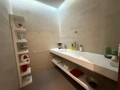 a bathroom with a large white sink and shelves at Very nice apartment with sea and pool views in Oulad Akkou