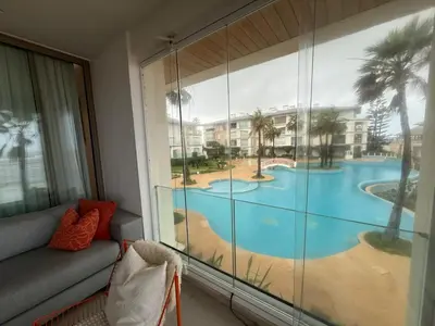 a room with a large window with a view of a pool at Very nice apartment with sea and pool views in Oulad Akkou