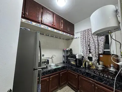a kitchen with a stainless steel refrigerator and wooden cabinets at Apartment 5 mins from downtown in Fès