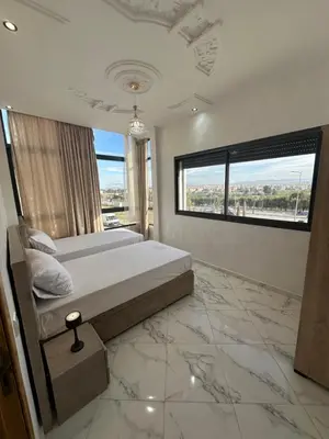 a bedroom with a bed with marble floors and a window at Appartement de standing supérieur à Fès en Route de Meknès in Douar Trhaïtia