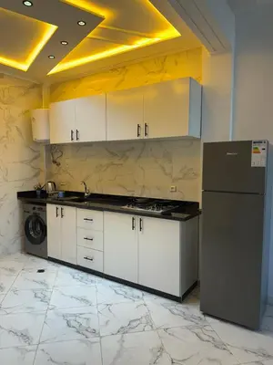 a kitchen with white cabinets and a black refrigerator at Appartement de standing supérieur à Fès en Route de Meknès in Douar Trhaïtia