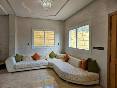 a living room with a couch and two windows at Villa rue imouzzer in Fès