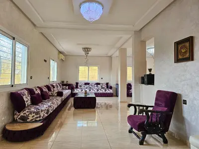 a large living room with purple couches and a table at Villa rue imouzzer in Fès