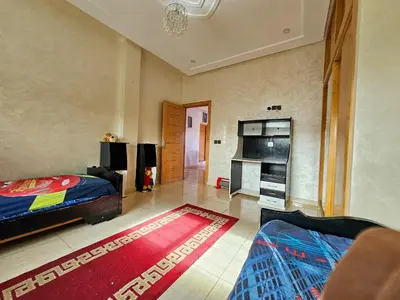 a bedroom with a bed and a living room at Villa rue imouzzer in Fès