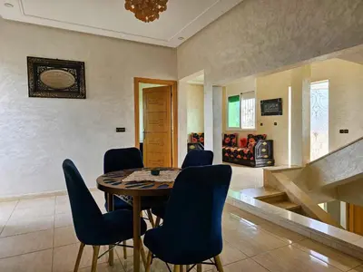 a dining room with a table and blue chairs at Villa rue imouzzer in Fès