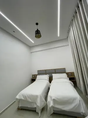 two beds in a room with white walls at Hôtel kairouan in Fès